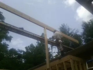 Carpenter setting a ridge beam over a new addition frame — Ice Dam Removal by Roofing Brothers in Delton