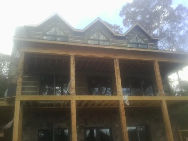 Dormers and porch framing on a large log home under construction — Roof Coating work by our crew in Delton