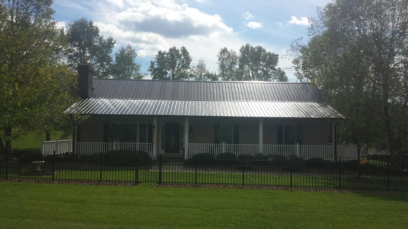 Gray metal roof on a brick ranch with a full width front porch — Gutter Guard Installation work by our crew in Delton